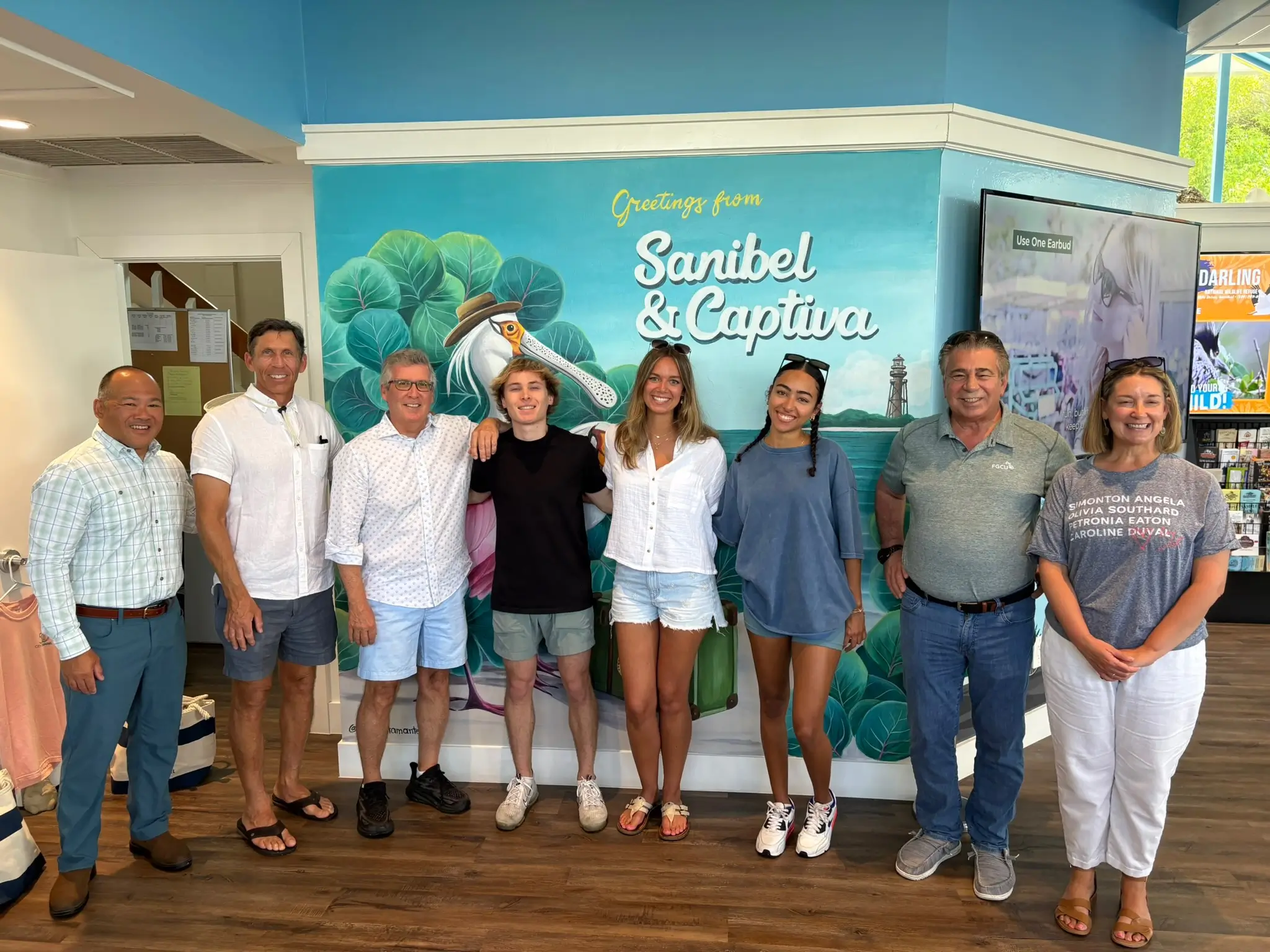 The Ain Hub team with Sanibel community leaders in front of a Greetings from Sanibel & Captiva mural